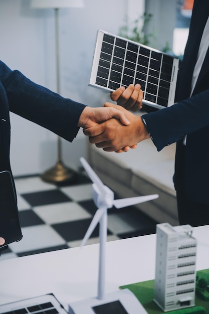 Two Young Engineers Expertise in Solar Cell Installation Meetings and Discussion in The Job Planning to Install Solar Photovoltaic Panels on Roof Top in The Office Room with Factory Building Plan