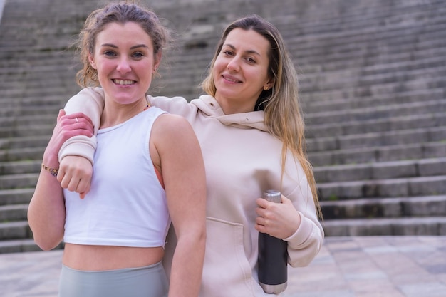 Two young fitness girls in a city park portrait of two female friends very happy after exercise