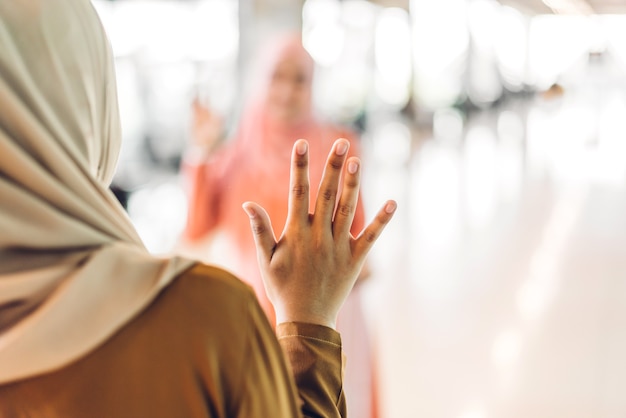 Two young friend muslim woman enjoying and having fun talking together waving hi and saying hello 