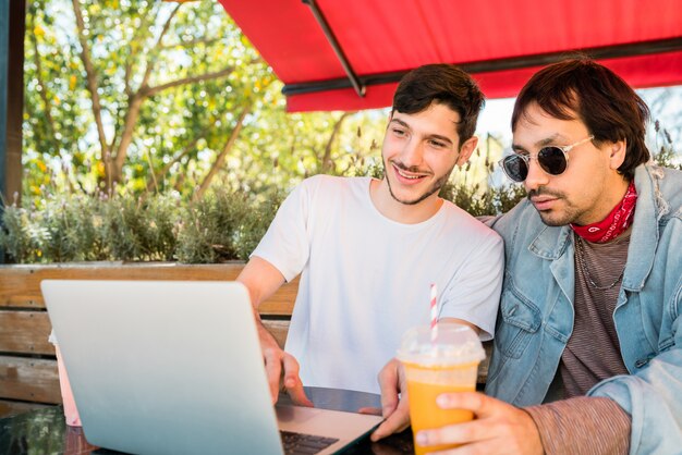 Two young friends using laptop at coffee shop.