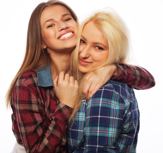 Two young girl friends standing together and having fun. Looking at camera.