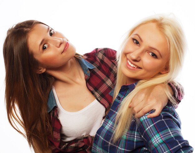 Two young girl friends standing together and having fun. Looking at camera.