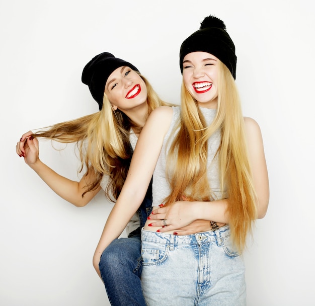 Two young girl friends standing together and having fun. Looking at camera.