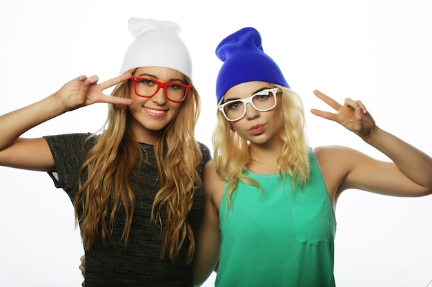 Two young girl friends standing together and having fun Showing signs with hands Looking at camera