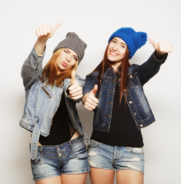 Two young girl hipster friends standing together