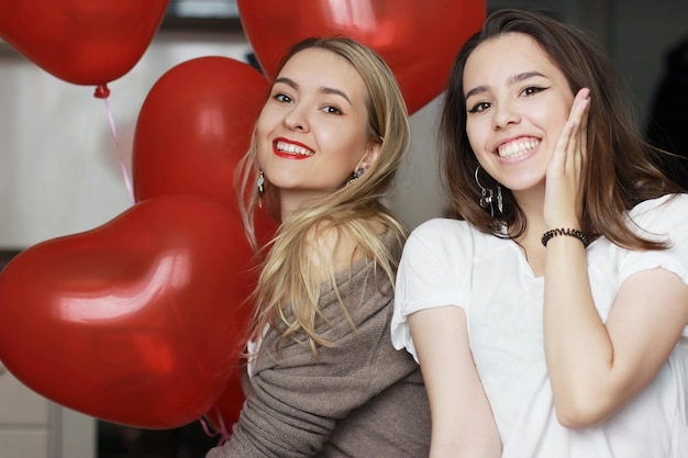 Two young girls are celebrating Valentine's Day. They're smiling.