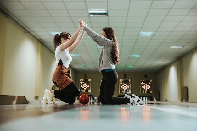 Two young girls giving high five at the bowling club.