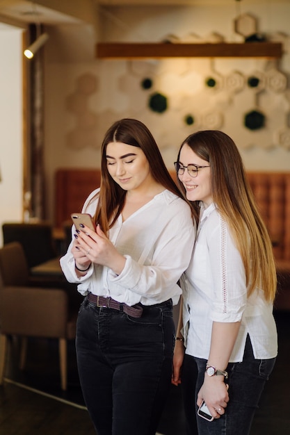 Two young girls using smart phone at the cafe