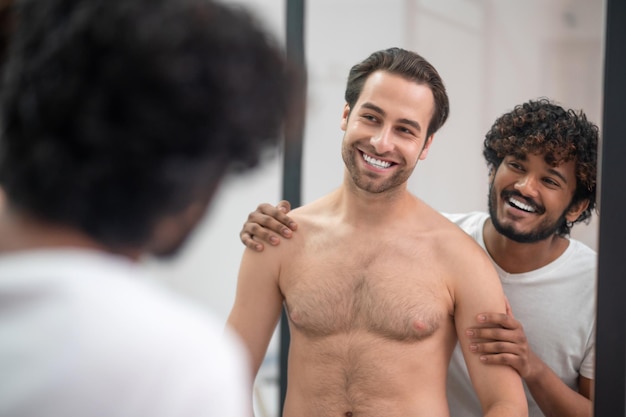 Two young handsome men stading in the bathroom at the mirror