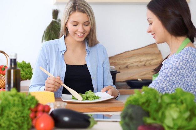 Two young happy woman making cooking in the kitchen Friendship and culinary concept