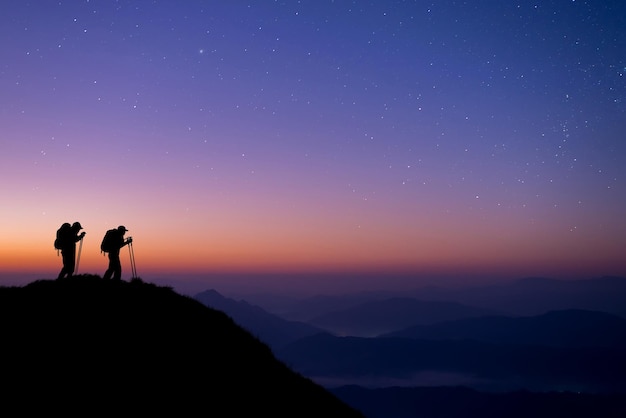 Two young hikers were standing at the top of the mountain looking at the stars and Milky Way.