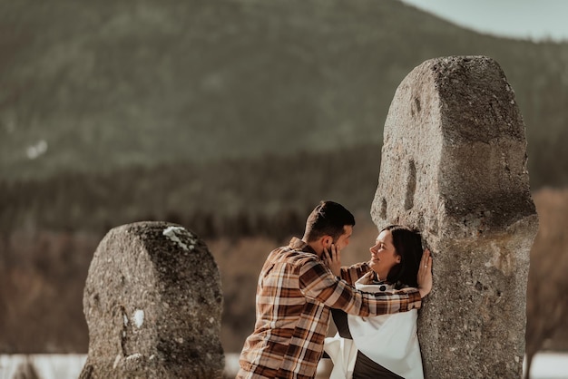 Two young lovers in love looking each other and leaning against the stone Passionate love Selective focus