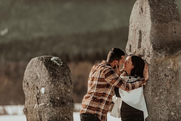 Two young lovers in love looking each other and leaning against the stone Passionate love Selective focus