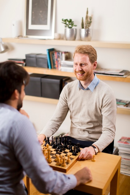 Two young men playing chess in room