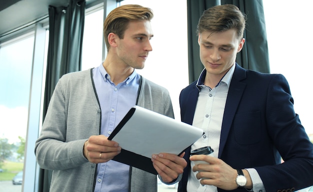 Two young modern men discussing work in the office.