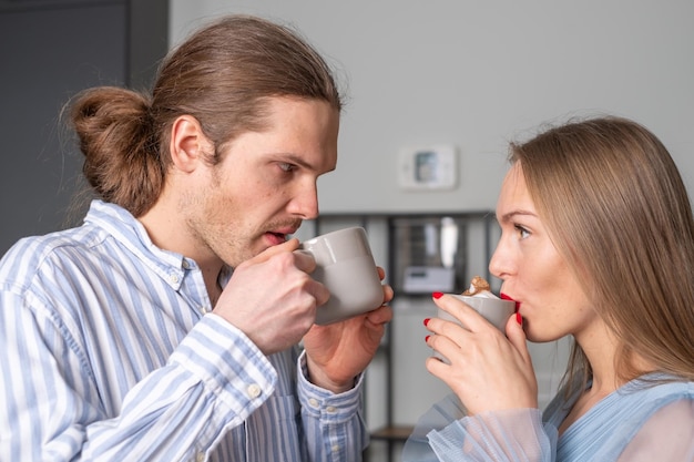 Two young people with beautiful long hair in light blue clothes are drinking coffee Copy space