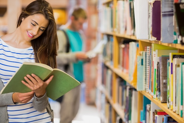 Two young students by bookshelf in the library