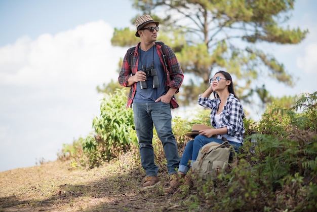 Two Young Traveler with backpack, are holding map relaxing in greens jungle and enjoying 