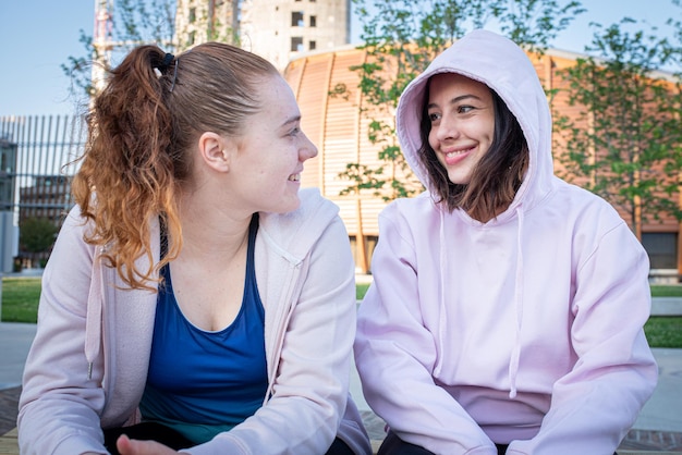 Two young woman taking rest after a joggin session, couple of girlfriends in a relaxation moment, lesbian couple concept, diversity and love