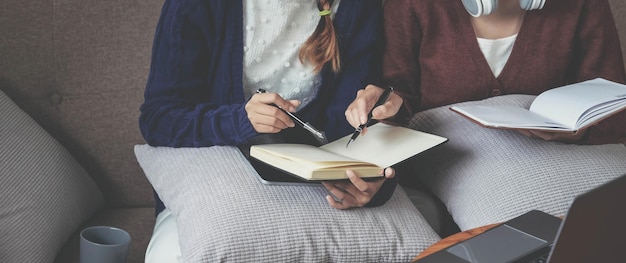 Two young woman thinking with a book on sofa in living room at home