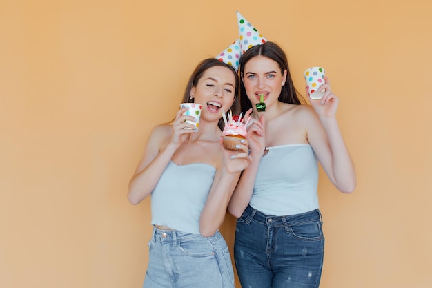 Two young women in birthday hats celebrating birthday