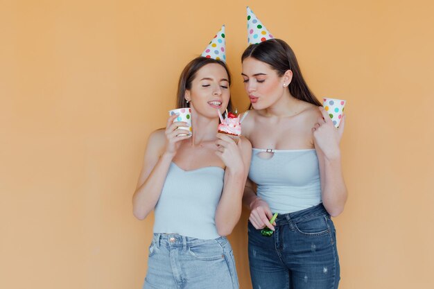 Photo two young women in birthday hats celebrating birthday