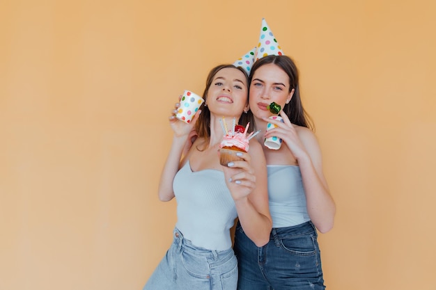 Photo two young women in birthday hats celebrating birthday