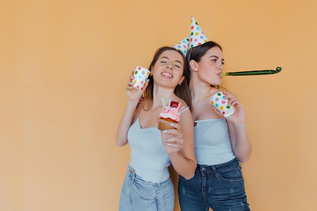 Photo two young women in birthday hats celebrating birthday