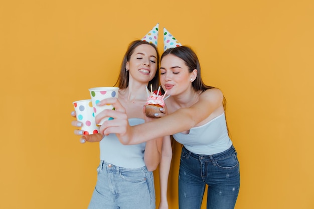 Photo two young women in birthday hats celebrating birthday