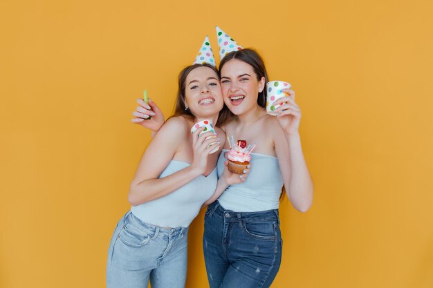 Photo two young women in birthday hats celebrating birthday