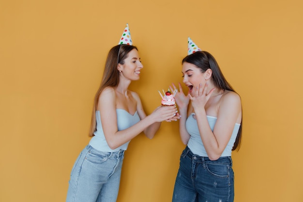 Photo two young women in birthday hats celebrating birthday