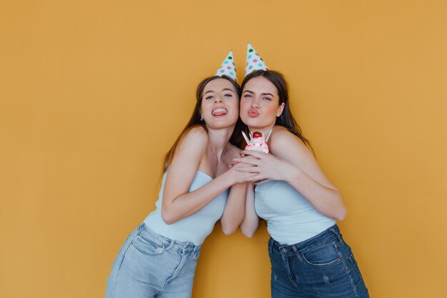 Photo two young women in birthday hats celebrating birthday