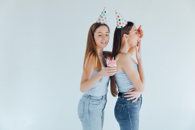 Two young women in birthday hats celebrating birthday