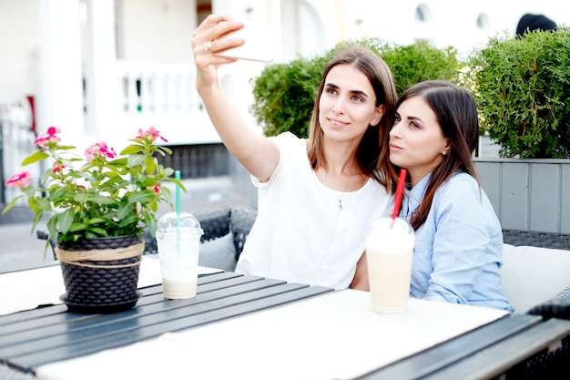 Two young women drinking morning coffee and making selfie