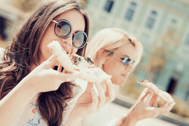 Two young women eating pizza