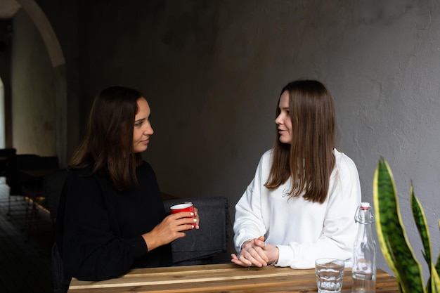 Two young women girlfriends communicate and have fun in a street cafe