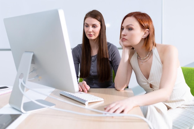 Two young women look at a computer screen while working on a design project