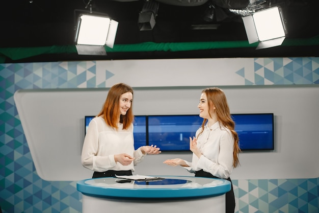 Two young women on set for TV interview, focus on women. Tv studio.