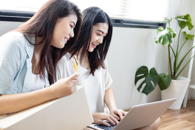 Two young women shopping online on laptop with credit card payment from home.