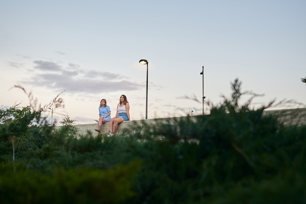 Two young women sitting in a city. They are meeting on a summer afternoon.