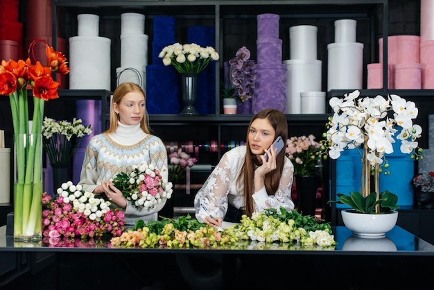 Two young women take orders by phone and make a beautiful festive bouquet