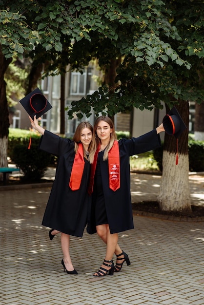 two young women wearing graduation caps pose for a picture