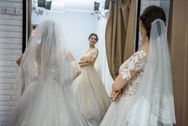 Two young women in wedding dresses posing before mirror