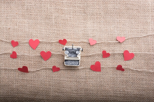 typewriter and love concept with heart shaped papers on linen threads