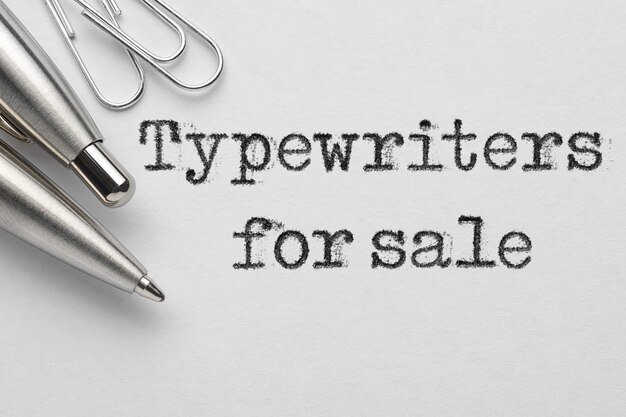 Photo typewriters for sale words typed near metal ballpoint pen and paper clips