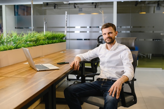 A typical manager in an office behind a desk works on a laptop high quality photo