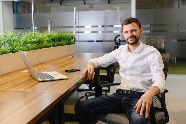 A typical manager in an office behind a desk works on a laptop high quality photo