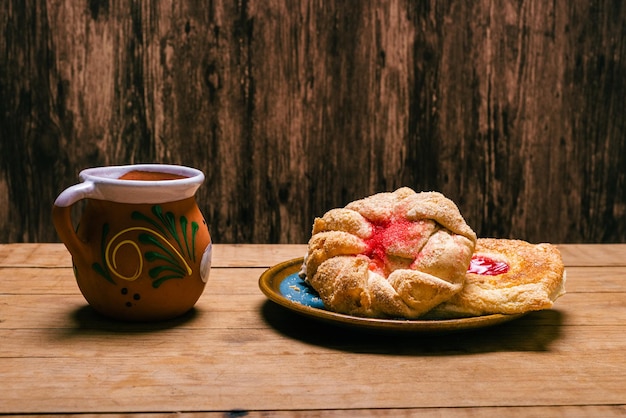 Typical mexican sweet breads and red ceramic mug on wooden table Typical Mexican desserts