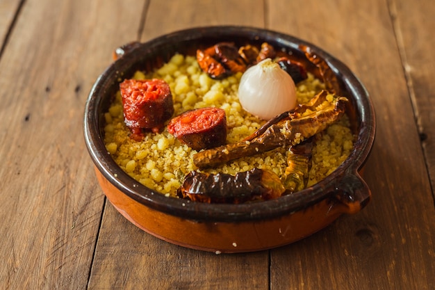 Typical spanish cuisine: an earthenware bowl with migas, onion, chorizo and dried peppers