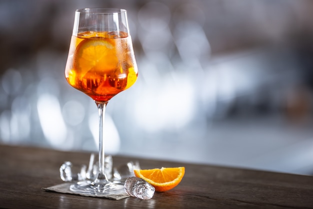 Typical summer sekt drink aperol spritz served in wine glass with aperol, prosecco, soda and a slice of orange.